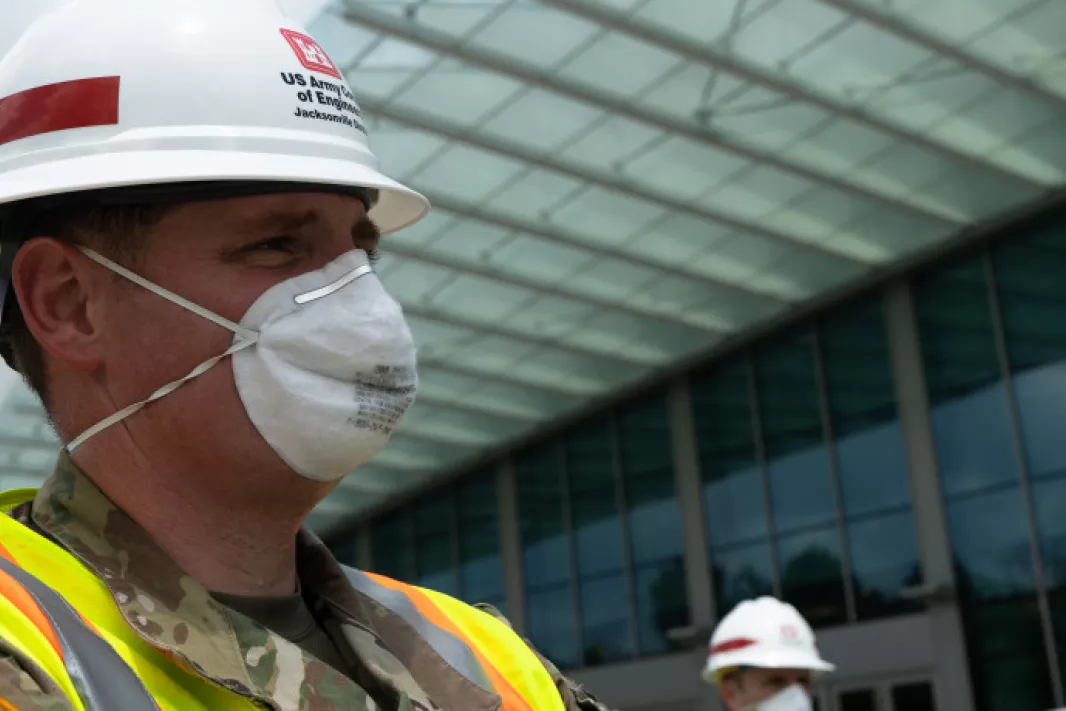 A man with a mask stands in front of the Miami Beach Convention Center